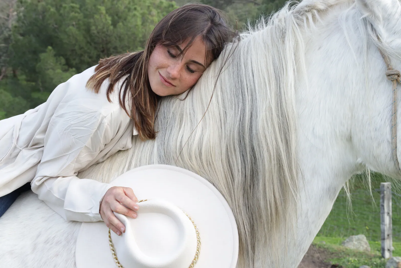 Una visitante apoya la cabeza en el cuello de un caballo blanco en Finca El Sarao